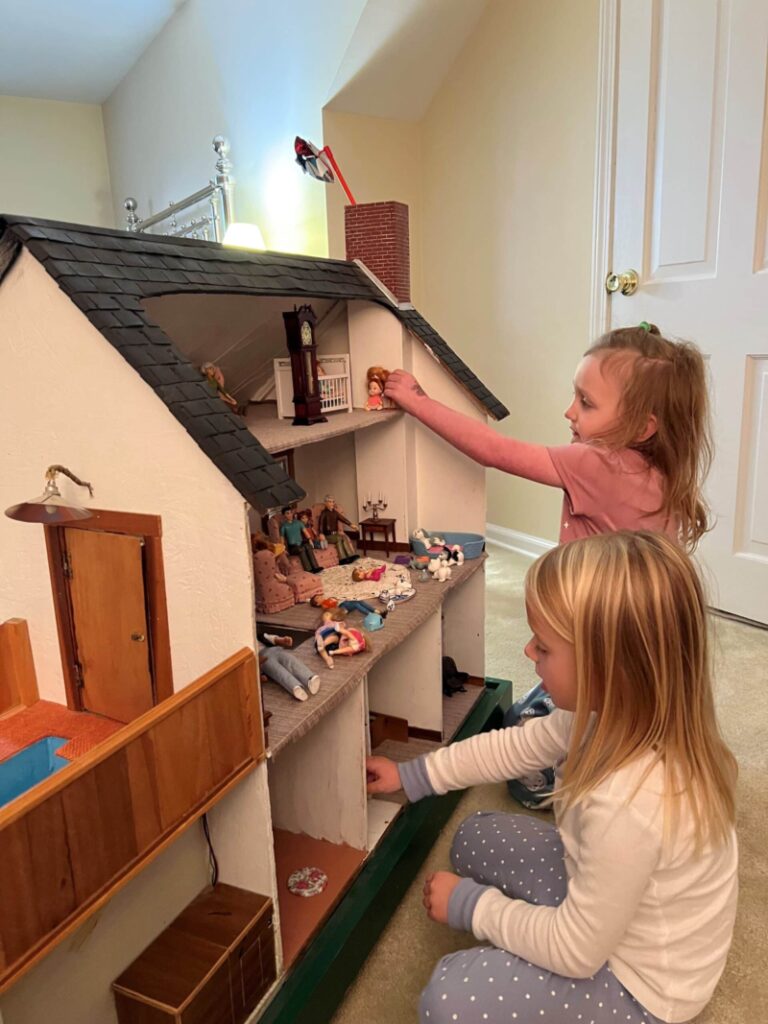 Two little girls playing in doll house.