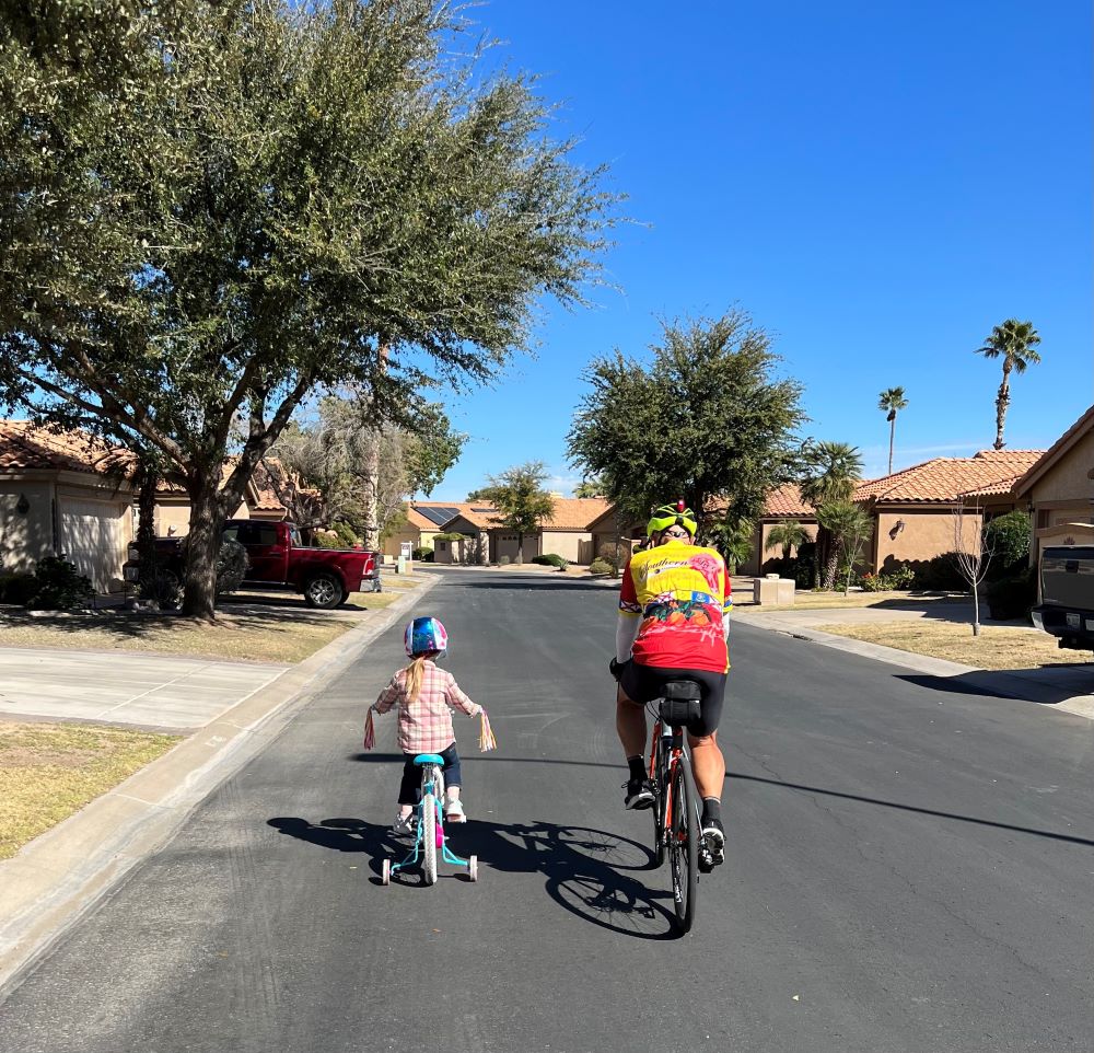 Papa and his granddaughter riding bikes together.