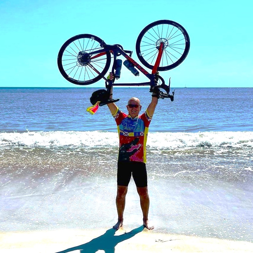 Man holding bicycle above his head by the Atlantic Ocean