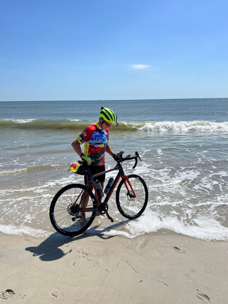 Man dipping his front tire in the Atlantic Ocean at the end of  cross-country ride