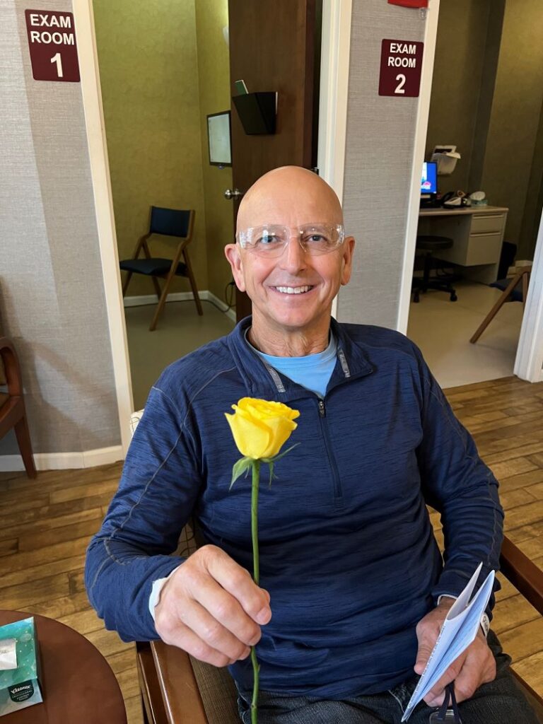 Man handing his wife a yellow rose following cataract surgery.